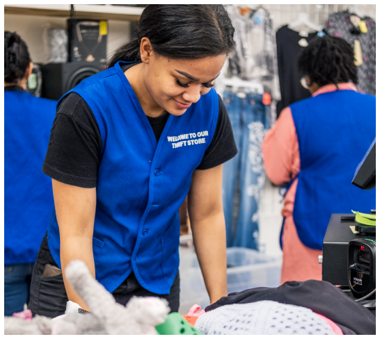 RWB Thrift employee wearing a blue vest scanning items.