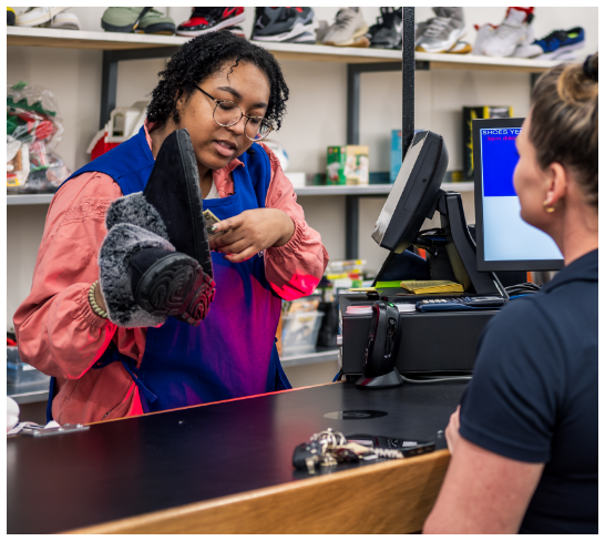 Customer purchasing shoes at the RWB Thrift checkout counter.